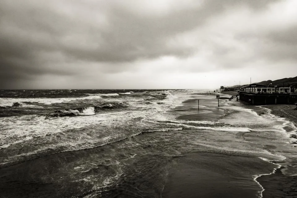 Storm waves running up a beach under a dark sky