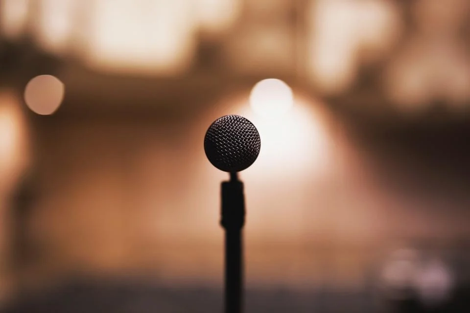 A single microphone on a stand against blurred warm lights