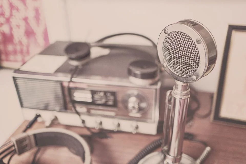 A vintage microphone beside an old radio and headphones