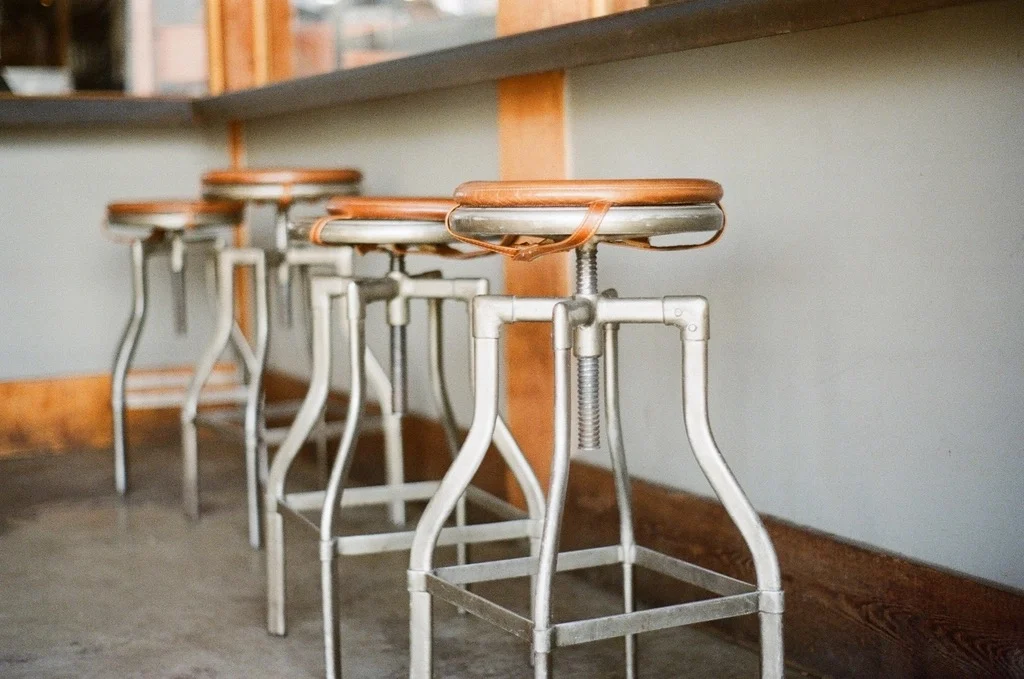 A row of empty metal stools at a counter