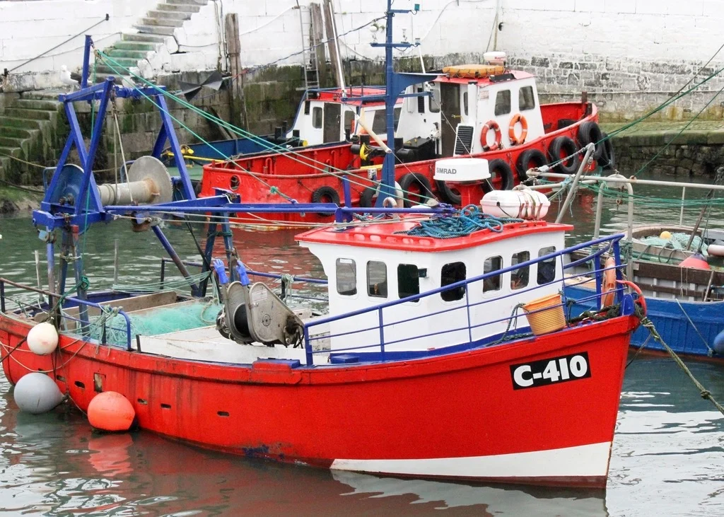 A red fishing boat tied up at a harbor dock